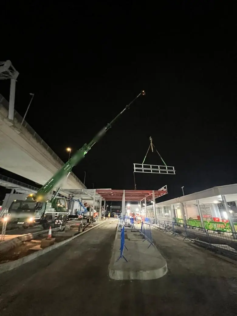Night lift under a flyover with a mobile crane